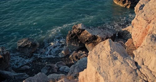 Scenic Beauty of Sunset Ocean Waves Crashing on Rocky Coastline