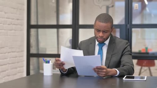 African Businessman Reading Documents in Office