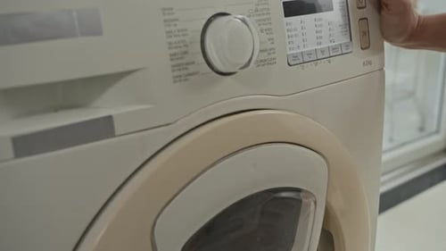 Person Setting Cycle of Washing Machine at Home
