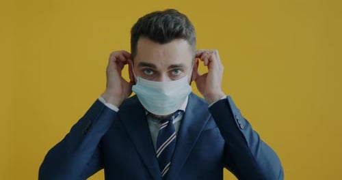 Man Putting on Surgical Mask Wearing a Suit