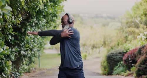 Old man, African with headphones and stretching in park, running and cardio with fitness