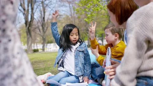 Mid adult teacher outdoors enjoying learning with children in city park