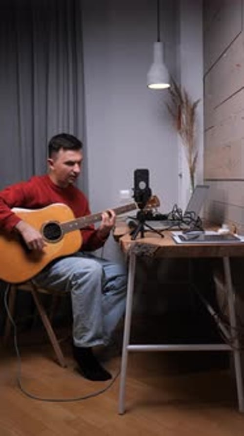 Young Man Playing Guitar and Singing Indoors