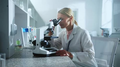 Woman Looking into Microscope in a Bright Lab
