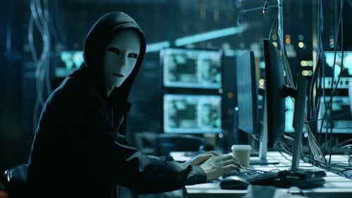 Anonymous Hacker Typing on Keyboard in Dark Room