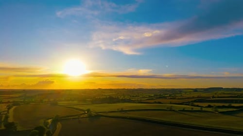 Sunset Time Lapse with Glowing Sun Over Agricultural Countryside Landscape Captured From Drone