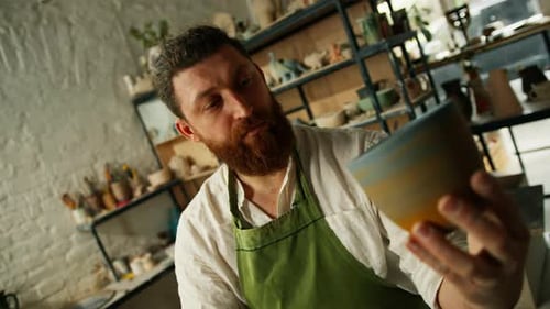 Potter Examining Ceramic Mug in Pottery Studio