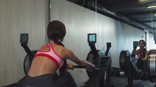 Woman Works Out on a Rowing Machine in Gym