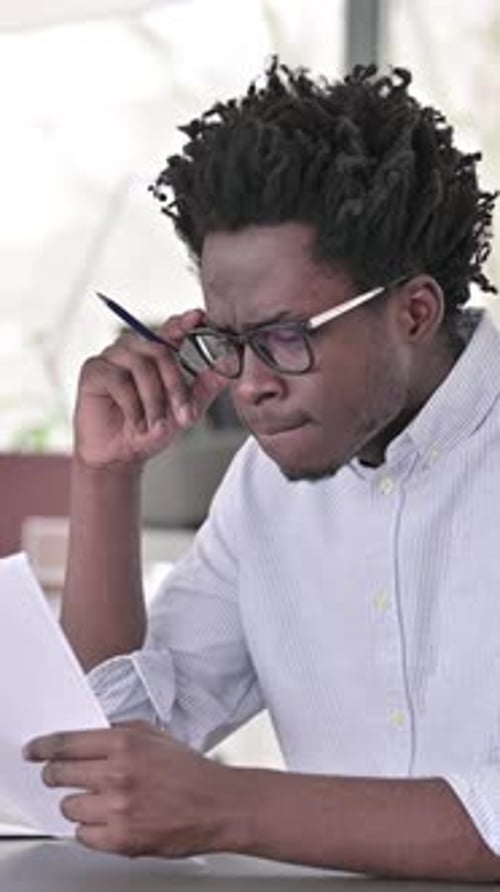 Thoughtful Man Analyzing Documents in Office Setting