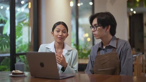 Colleagues Reviewing Laptop in Cafe