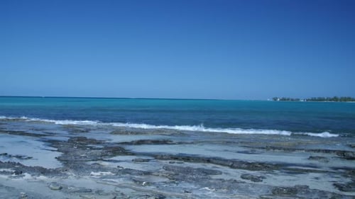 Wunderschöne Meereswellen an der felsigen Küste mit einer Insel im Hintergrund