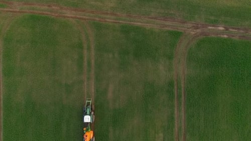 Pesticide and fertilizer spraying on the field aerial view with tractor