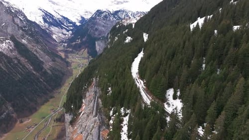Railway among evergreen forest and near steep Switzerland mountain edge