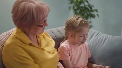 Grandmother and Granddaughter Reading a Book at Home