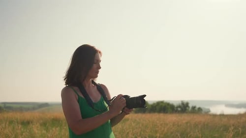 Female Tourist Holding Camera in Golden Field During Summer