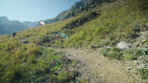 A mountain biker is riding down an alpine trail with speed