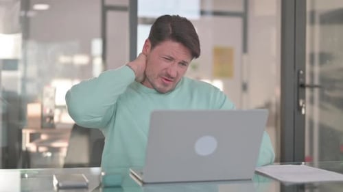 Man Working on Laptop with Neck Pain in Office