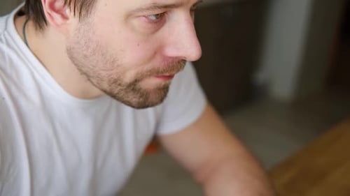 Handsome Bearded Man is Eating Green Fresh Vegan Salad in the Kitchen at Home Male Sitting at Table
