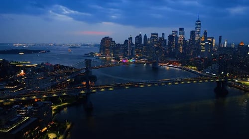 Beautiful New York bridges at night. Multiple cars move by the bridges with headlights on
