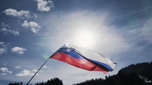 Slovenian Flag Waving in the Wind Against Blue Sky