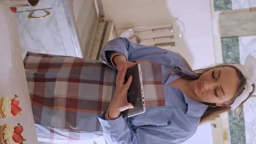Woman With Tablet in Kitchen With Cupcakes
