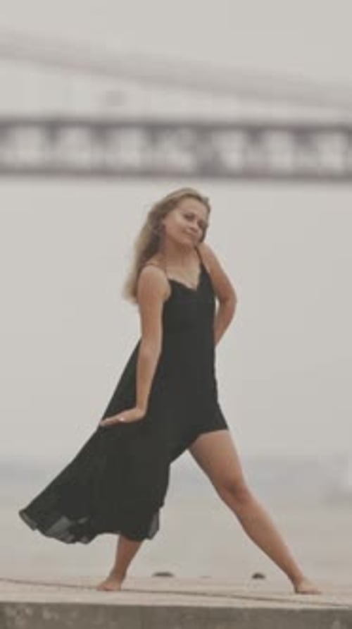 Woman in Dress Dancing Barefoot on Concrete Shore