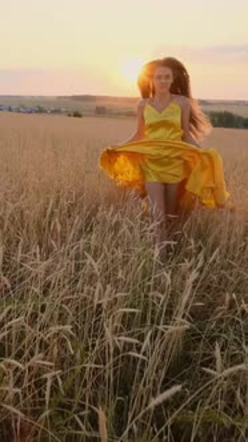 Young Woman in Yellow Dress Twirling in Golden Field During Sunset with Warm Light and Nature