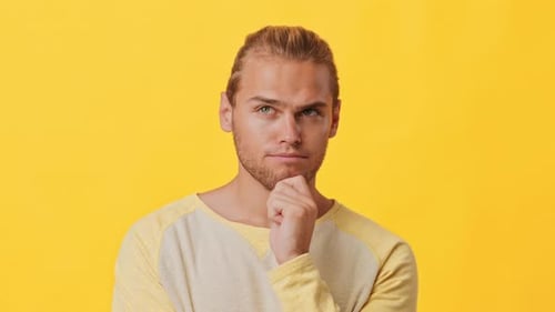 Young Man Thinking Against Yellow Background