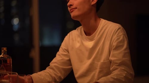 Man Sipping Drink at Home at Night