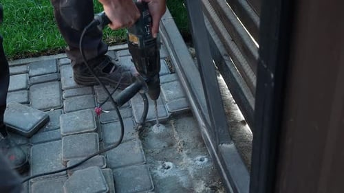 Builder Drills a hole in the wall with a Hammer Drill. Close-up of hammer drill perforator