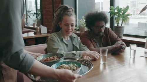 Unrecognizable Waitress Bringing Two Bowls on Tray, Putting It on Table in Cafe