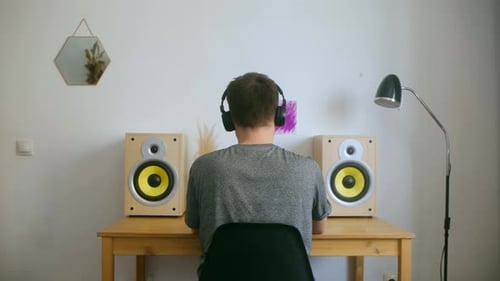 Man with Headphones at Desk with Speakers