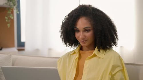 Woman Smiling Using Laptop While Sitting on Couch