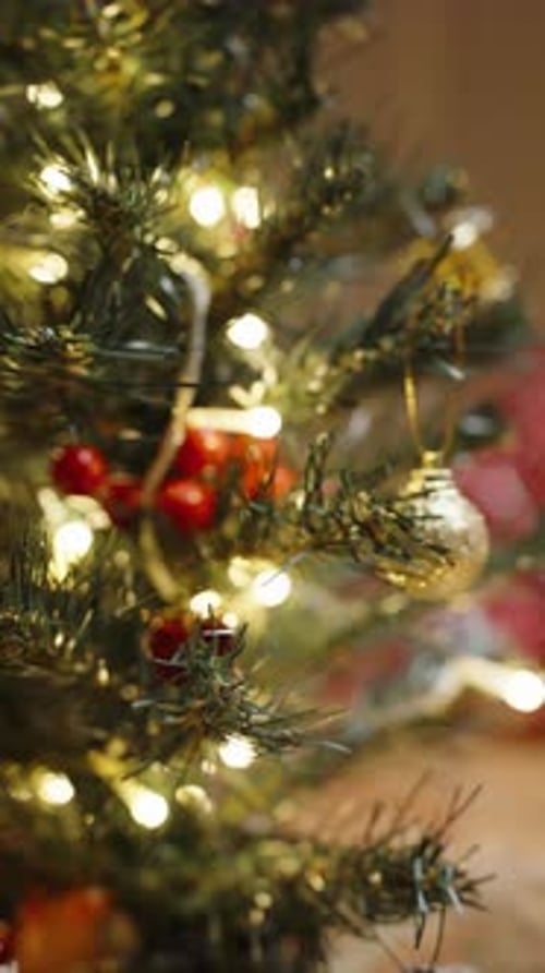 Vertical video. Close-Up of a Christmas Tree Ornament with a Woman in a Red Sweater Working on a Cra