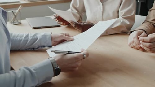 Kaukasischer Bewerber unterzeichnet Arbeitsvertrag und schüttelt der kaukasischen Personalabteilung die Hand