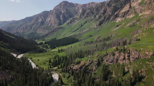 River Flowing Through Green Valley Surrounded By Mountains
