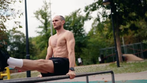 Muscular Man Doing Dips on Parallel Bars in a Park