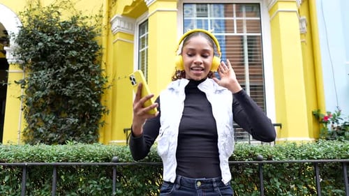 African american urban woman dancing listening to music at city