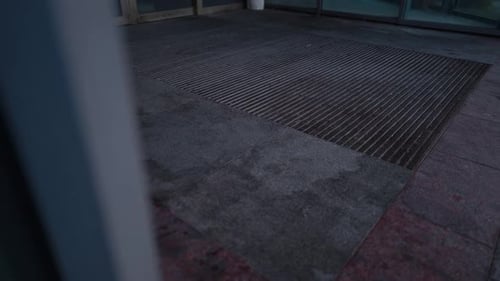 Urban Entrance Featuring Textured Ground and Grating Surrounded By Low Light and Shadows at Twilight