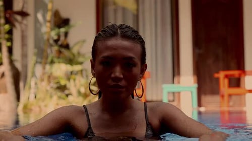 Woman Leaning on Edge of Tropical Pool