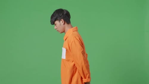 Side View Of Asian Male Prisoner In Handcuffs Walking On The Green Screen Background