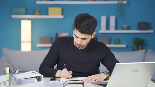 Young man looks working at home focused on laptop.
