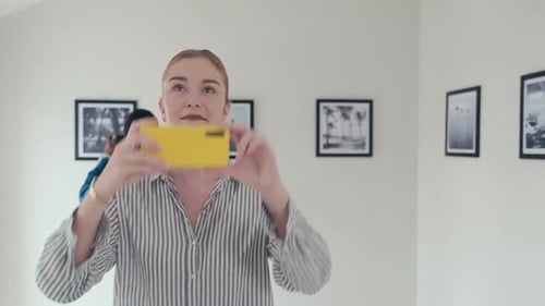 Woman Taking Pictures with Phone of Photo Exhibition in Gallery
