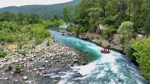 Gruppe von Menschen beim Rafting auf einem türkisfarbenen Fluss, umgeben von üppigem Grün und felsigen Ufern