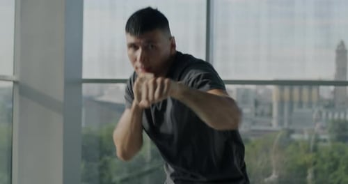 Man Shadow Boxing in Front of City Window