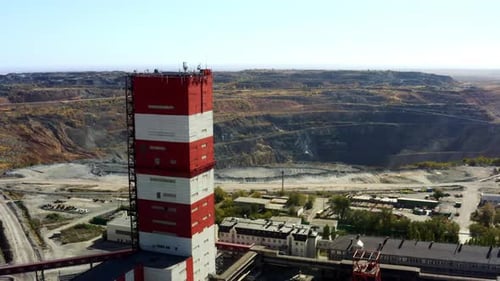 An Impressive Industrial Tower Stands Tall Towering Over and Surveying a Vast Mining Site Below It