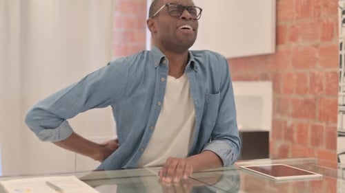 African Man with Back Pain Sitting in Office
