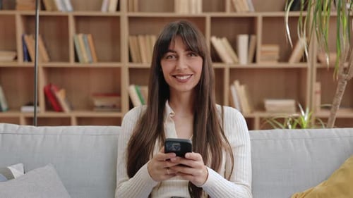 Smiling woman using mobile phone on a sofa