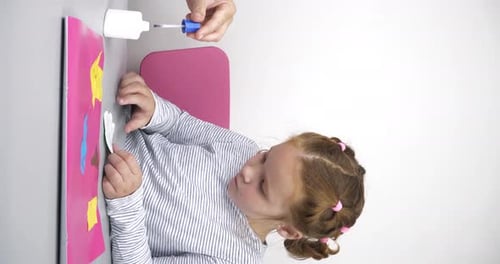 Mother Helps Her Daughter Put Glue on Colored Paper and Stick to the Picture