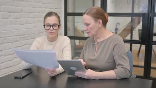 Two Women Discussing Business at Office Desk